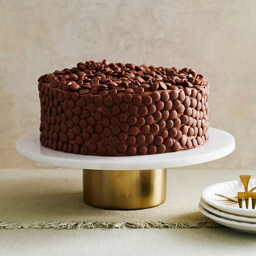 chocolate cake decorated with chocolate drops on marble cake tray
